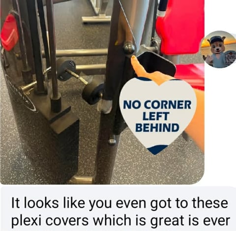 Gym equipment with orange and black protective plexiglass covers displaying No Corner Left Behind sticker and user profile icon